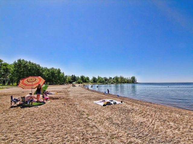 Some people on a sandy beach with people in the water swimming