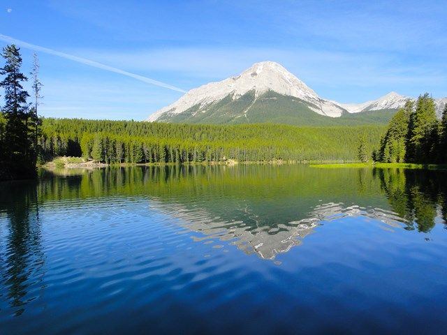 Beautiful lake surrounded by trees with the mountains in the background.