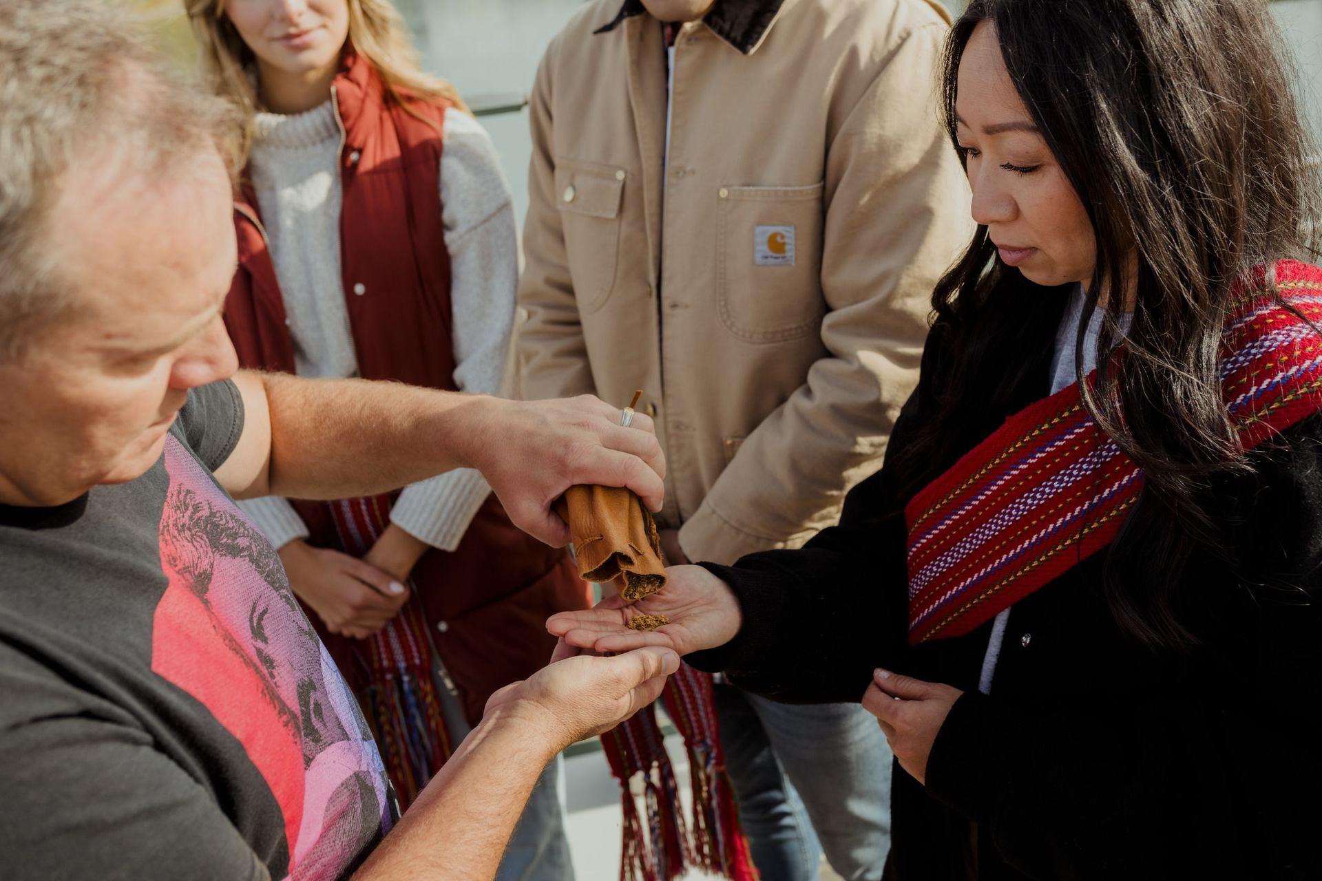 Métis guide sharing Indigenous history & culture with guests (Geo-Explorers) and offering tobacco together on a Talking Rock Tour.