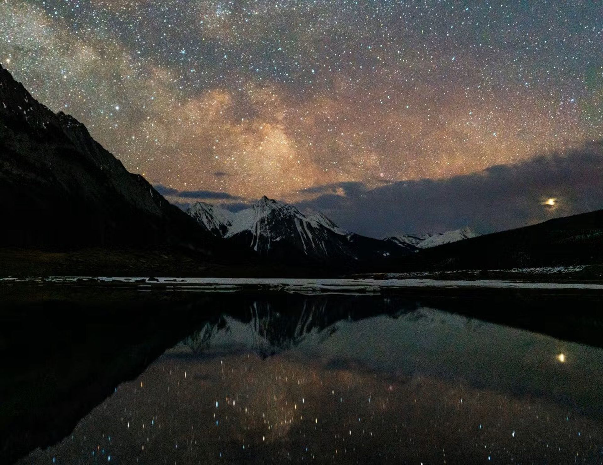Starry skies above a winter mountain landscape.