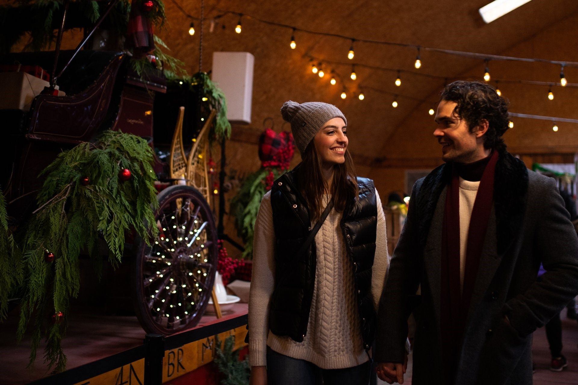 A couple walks hand in hand next to a Christmas display.