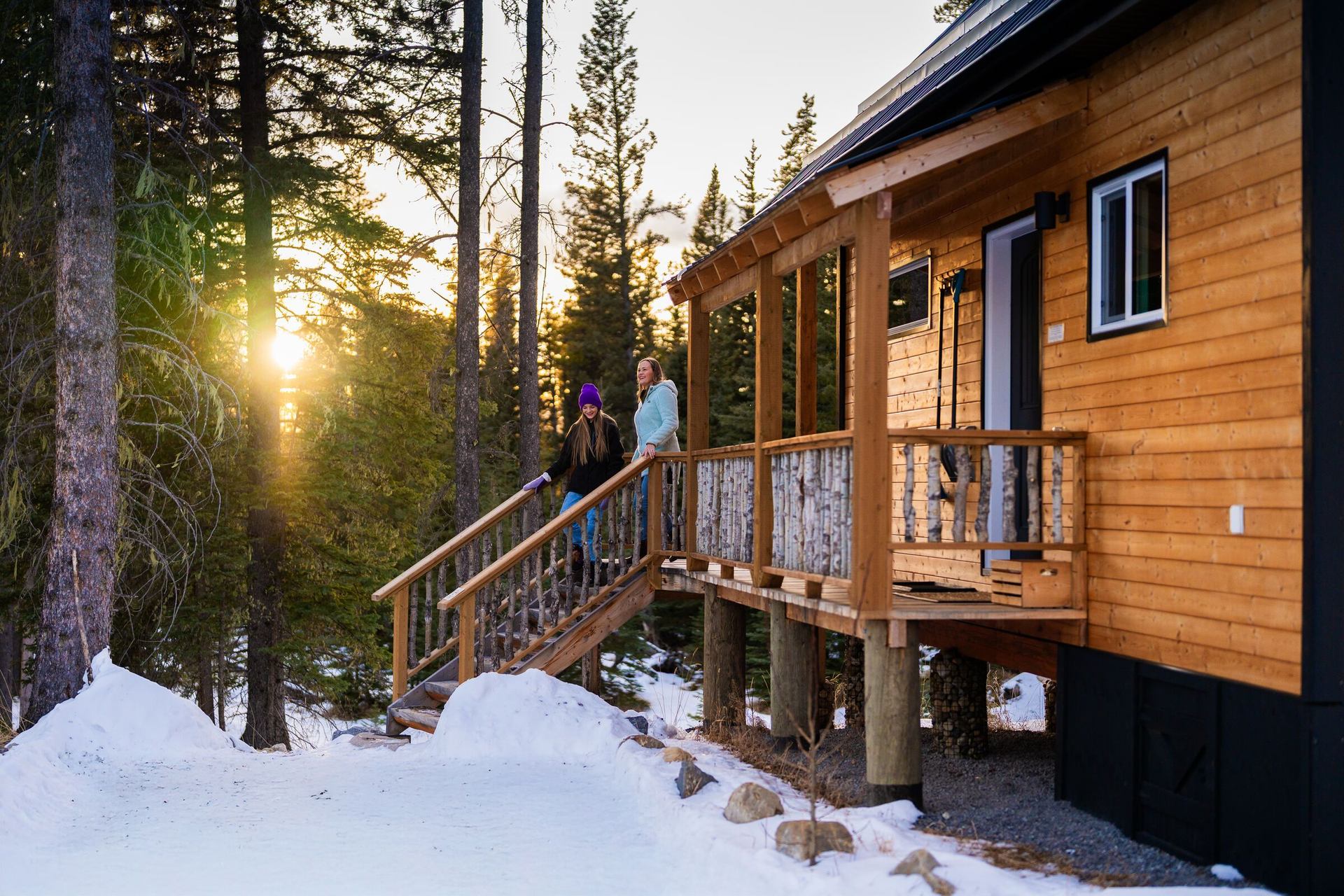 Two ladies going down the stairs of the veranda out front of a cabin at Expanse Cottages.