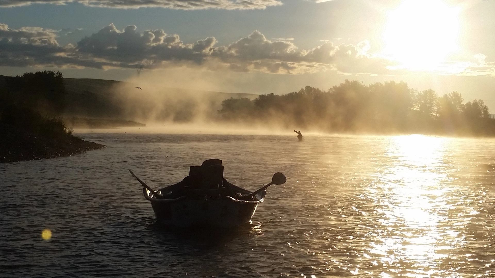 A boat on the water with the sun in the distance.