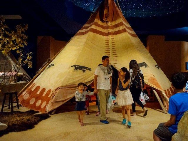 A family explores an indigenous teepee museum exhibit.