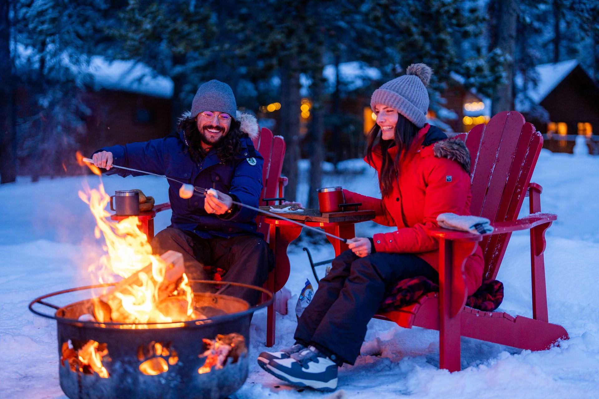 Couple sitting around campfire pit making smores at Baker Creek Cabins