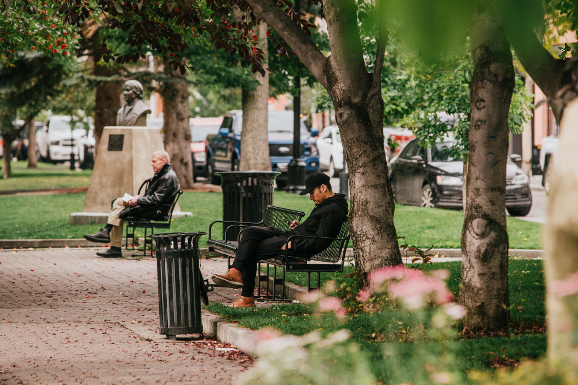 Men site on park benches in a city park.