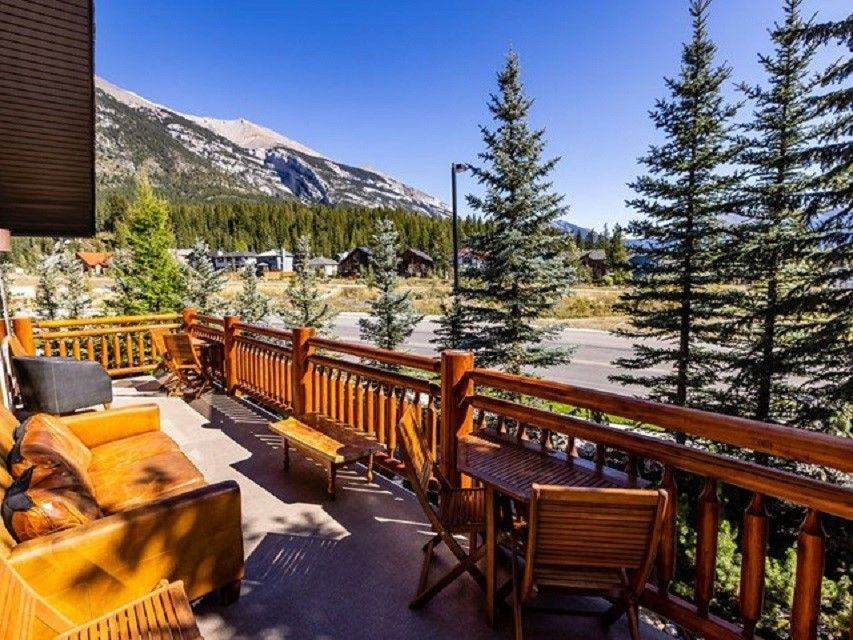 View of pine trees and mountains from a rustic wooden deck.