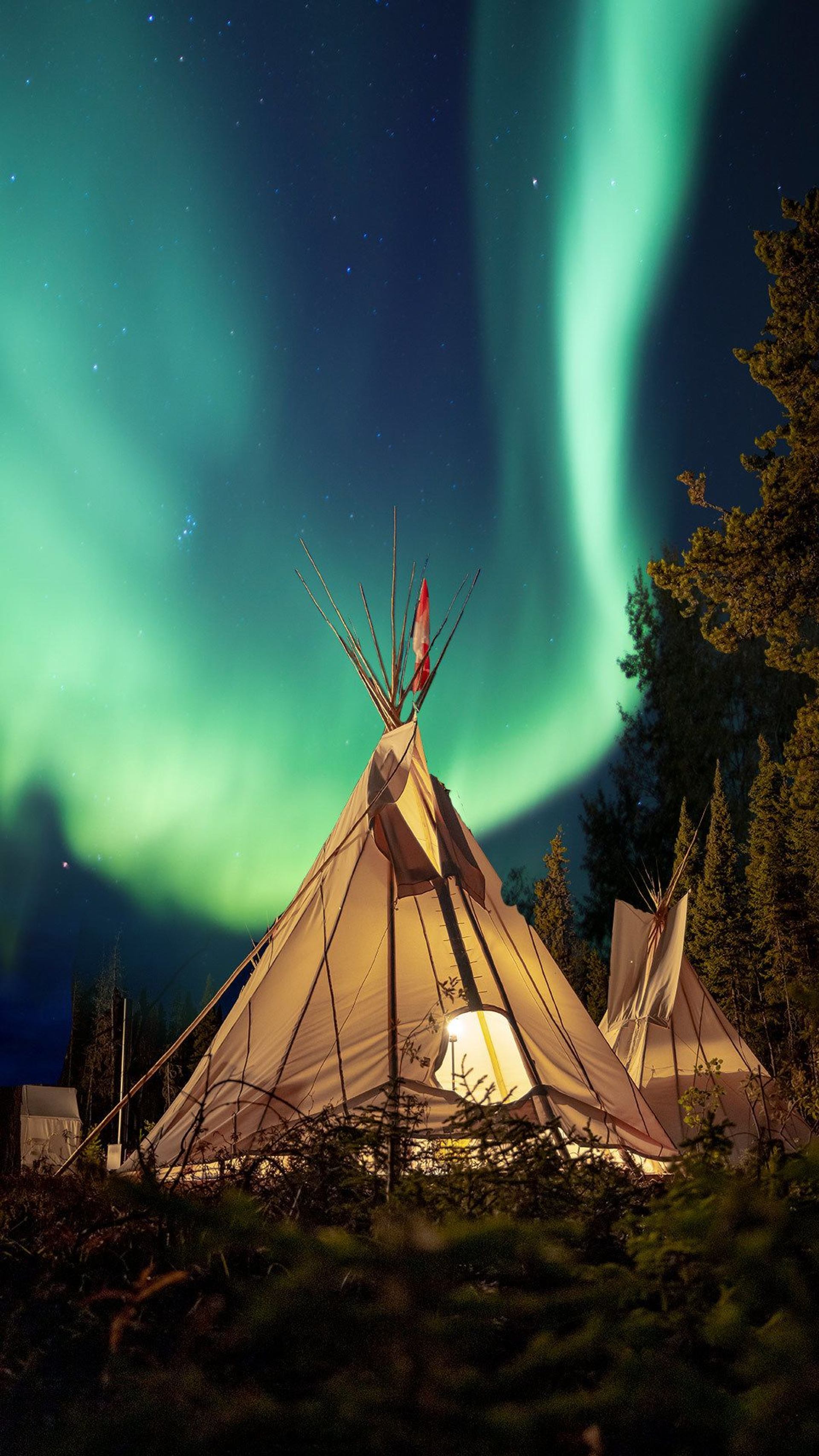 Greenish Northern Lights dance above a teepee.