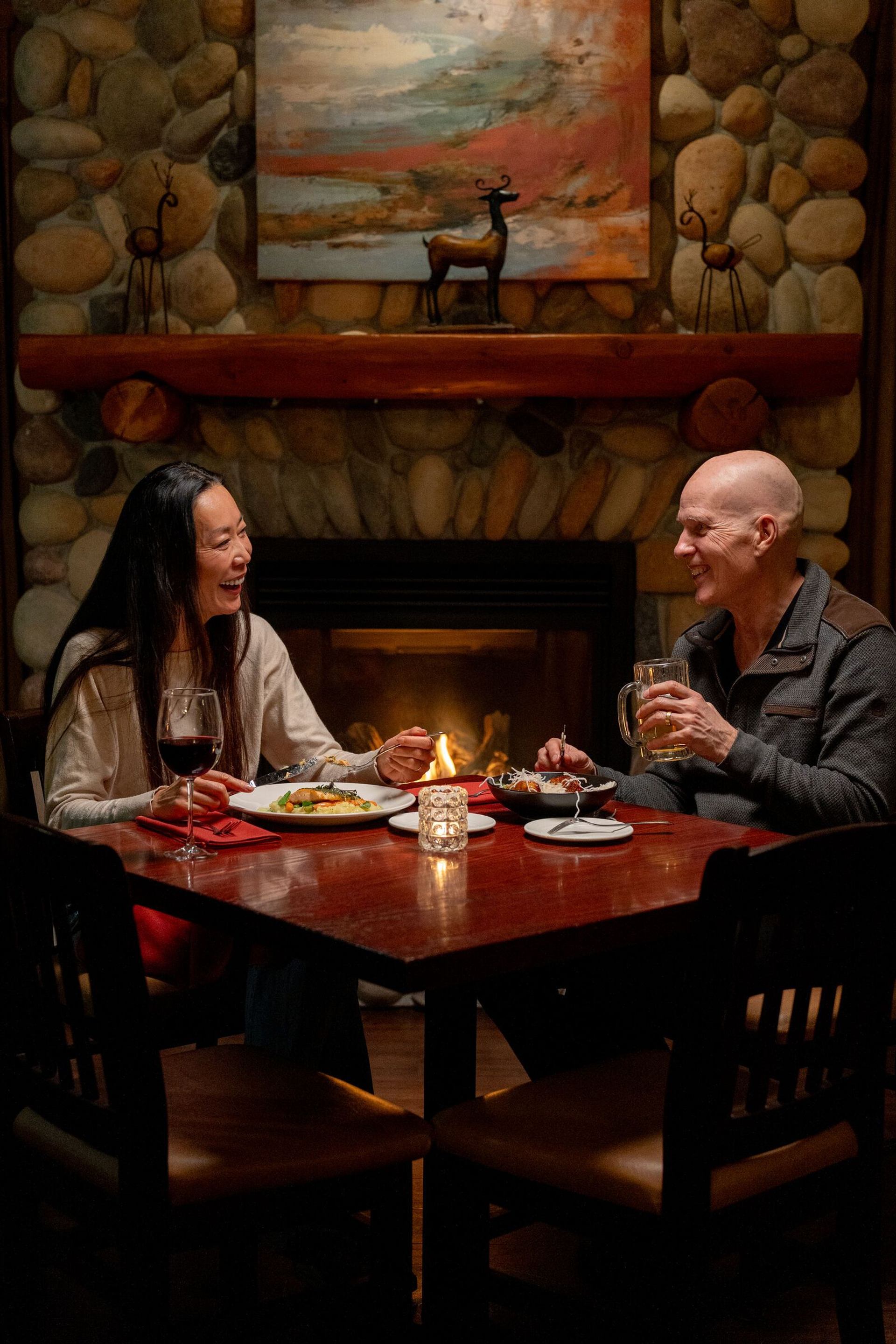 A couple enjoying dinner sitting next to the fireplace at The Prairie Creek Inn 