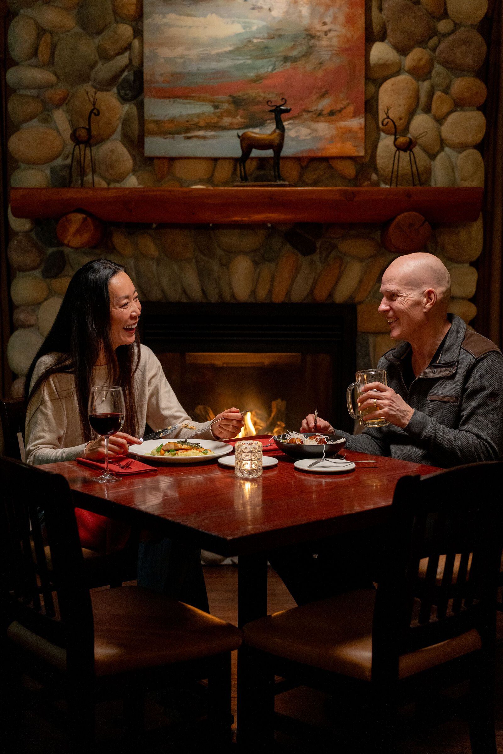 A couple enjoying dinner sitting next to the fireplace at The Prairie Creek Inn