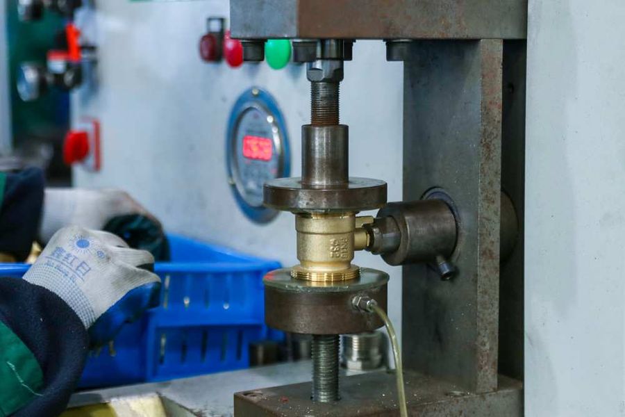 Brass valve body clamped in a bench test rig with a digital pressure readout in an in-house testing room