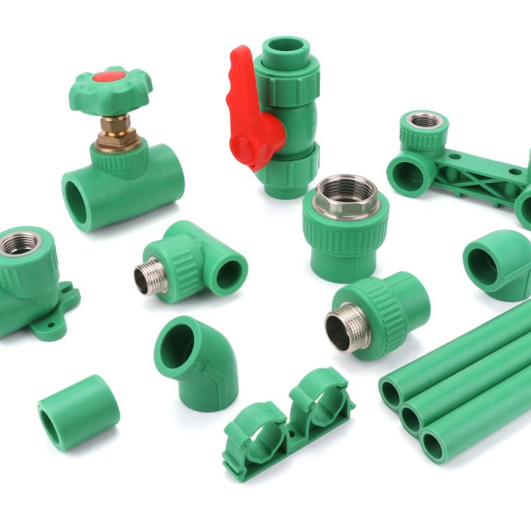 Assortment of green PP-R fittings including a stop valve, a red-handled ball valve, elbows, sockets, tees and short pipe lengths arranged on a white background