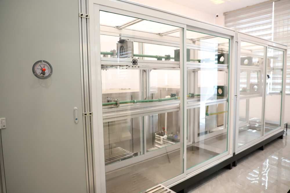 Green PP-R pipe samples mounted in glass-fronted pressure-test cabinets with a pressure gauge in IFAN's testing lab