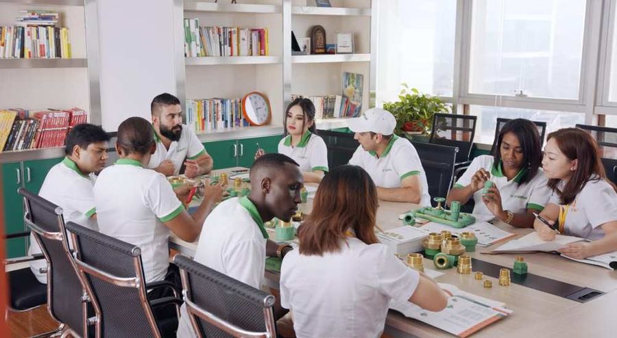 International sales and technical team examining PP-R and brass fittings with technical documents open on a boardroom table