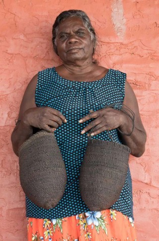 Margaret Rarru with Märrma’ mul mindirr (two black dilly bags) / Image courtesy: The artist and Milingimbi Art and Culture, Milingimbi