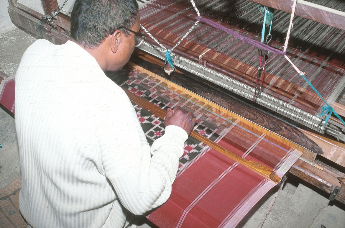 Ramulu weaves a telia rumal length on a pit loom with fly shuttle in Puttapaka, 1999 / Photograph: Dana McCown
