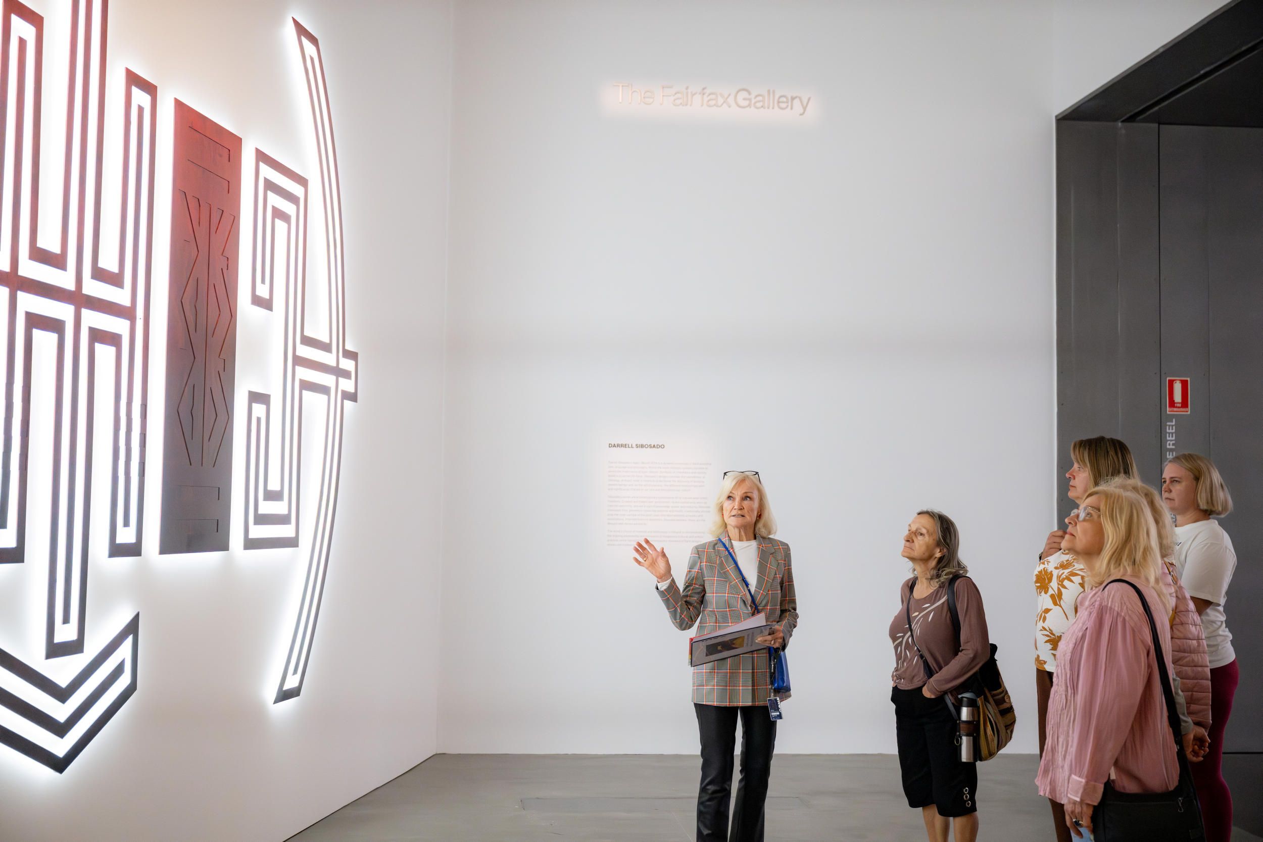 A Volunteer Guide engages visitors on a tour at the Gallery Of Modern Art / Installation View / Photograph: C. Callistemon / © QAGOMA