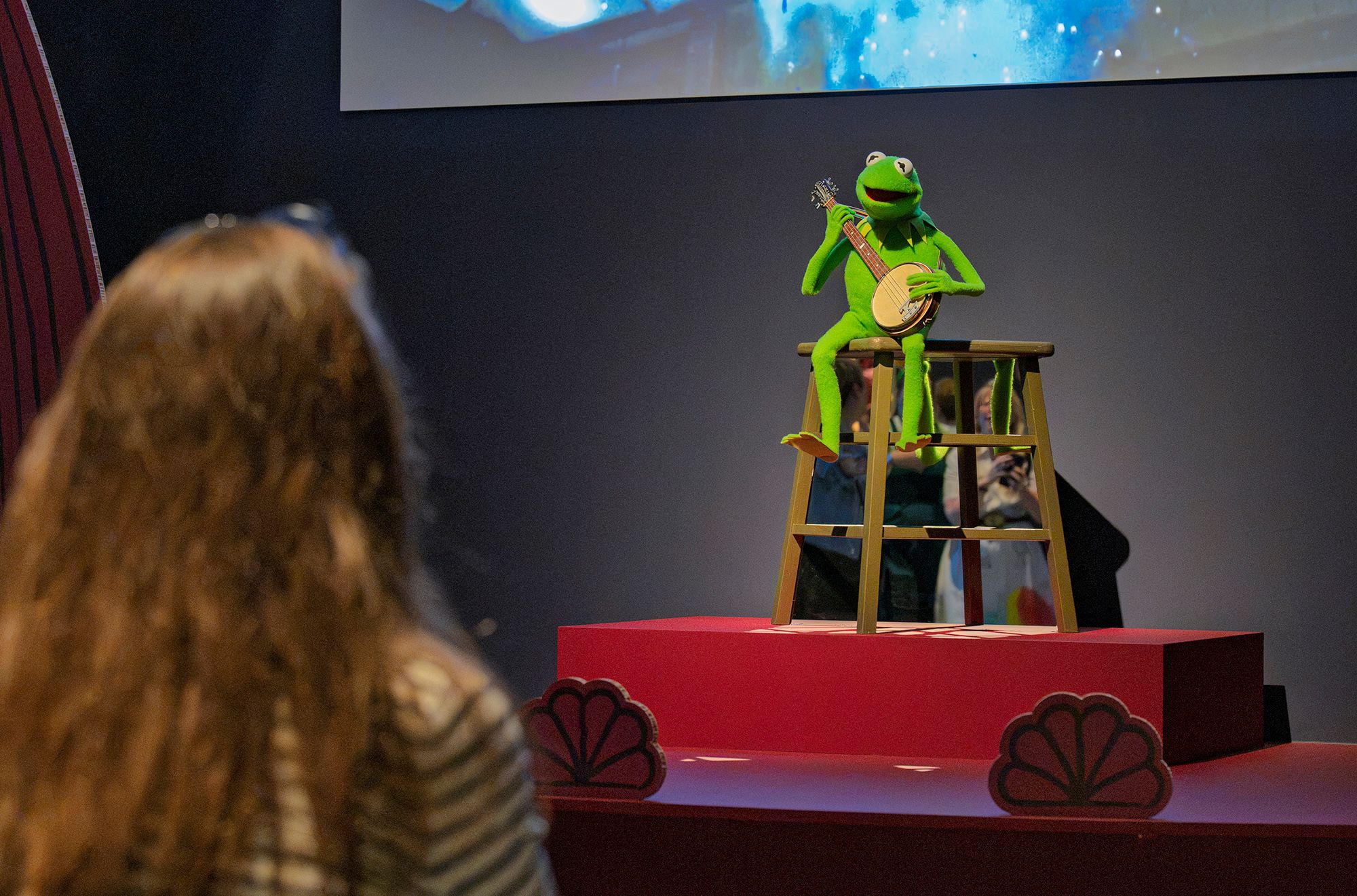Installation view of 'Make, Believe, Magic: The Worlds of The Jim Henson Company', Gallery of Modern Art (GOMA), Brisbane, 2026, featuring ‘Kermit the Frog’ puppet with banjo c.1979–90 from The Muppet Movie 1979 / Collection: Courtesy of The Walt Disney Company / © Disney Enterprises, Inc. / Photograph: N Umek © QAGOMA