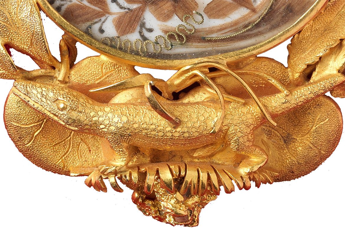 Hogarth, Erichsen & Co. (Manufacturer), Australia c.1854–65 / Julius Hogarth (Designer), Australia 1821–79 / Conrad Erichsen (Maker), Australia c.1825–1903 / Archer mourning brooch c.1860 / Matt gold with oval section (containing hair), embroidered over silk with seed pearls, chain and pin / 5.8 x 5.6 x 1.3cm / Gift of Mrs Alison Forster 1990 / Collection: Queensland Art Gallery | Gallery of Modern Art