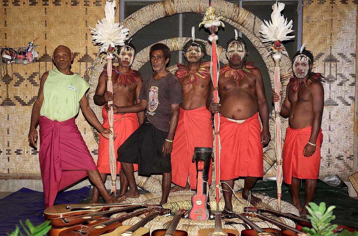 Jackson Pinia leader of the Amidal Tribes String Band with senior band members. Holding on to ceremonial spears, Rumus and an Ulang they stand in front of the APT9 Lolois of Tutanas before the perform a song especially written by Pinia about the Tutanas. Photograph Gideon Kakabin