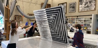 Turning Gordon Bennett’s painting Number three 2004 face down after cleaning / Gift of Leanne Bennett through the Queensland Art Gallery | Gallery of Modern Art Foundation 2020. Donated through the Australian Government’s Cultural Gifts Program / Collection: Queensland Art Gallery | Gallery of Modern Art / © The Estate of Gordon Bennett / Photograph: K Wilson © QAGOMA