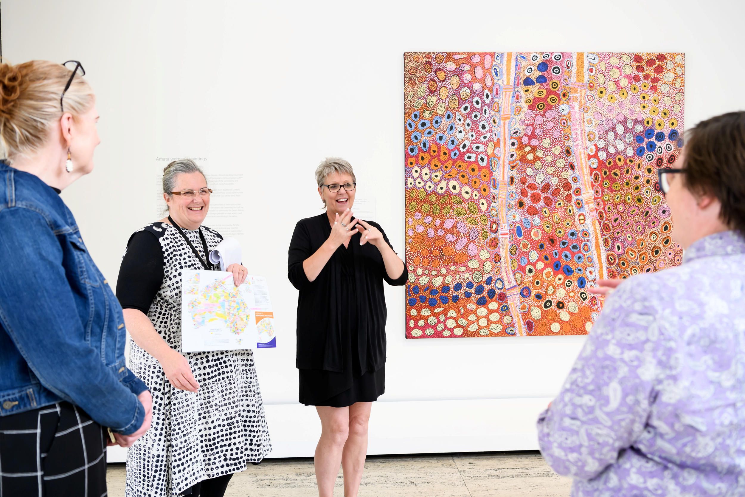 Visitors on an Auslan interpreted tour featuring Kunmanara Kawiny (Artist) / Mona Mitakikil Shepherd (Collaborating artist) / Tjimpayie Prestley(Collaborating artist) / Seven sisters 2011 / Synthetic polymer paint on linen / Purchased 2012 with funds from Margaret Mittelheuser, AM, and Cathryn Mittelheuser, AM, through the Queensland Art Gallery Foundation / Collection: Queensland Art Gallery / © The artists / Photograph: Chloe Callistemon