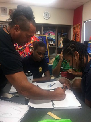 Laurie Nona sketches a design with students Pelista Pilot and Gongai Nona.