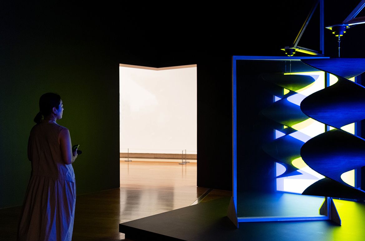 Taree Mackenzie, Australia b.1980 / Pepper’s ghost, wind turners, blue and yellow 2018 / Acrylic, foam core, steel, reflective tinting, LEDs, motor, paint, wood, vinyl / Reflective screen: 200 x 120 x 7cm; hanging sculpture: 150 x 80 x 80cm; brackets: 120 x 120cm / Purchased 2020 with funds from the Future Collective through the QAGOMA Foundation / Collection: Queensland Art Gallery | Gallery of Modern Art / © Taree Mackenzie