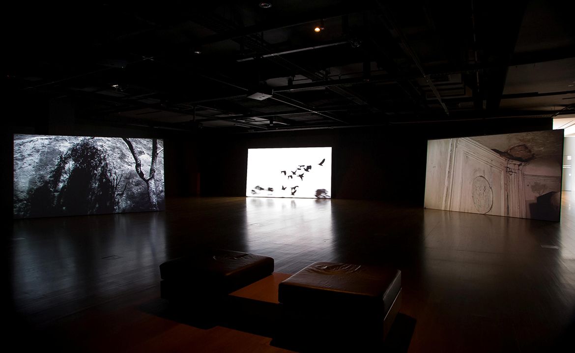 Hiraki Sawa, Japan b.1977 / O 2009, installation view  / Multi-channel video installation: 3-channel video projection exhibited from hard drive, HD video, 16:9, colour and black and white, 5-channel sound, 8:00 minutes; 10 channel video installation exhibited on customised LCD monitors, HD video transferred to DVD, 16:9, black and white, silent, 00:60 seconds; 5- channel sound by Organ Octet (edited by Dale Berning) exhibited on customised spinning speakers; customised metal light frames and light-bulb fixtures / Purchased 2010. QAG Foundation / Collection: Queensland Art Gallery | Gallery of Modern Art / © Hiraki Sawa / Photograph: N Harth © QAGOMA