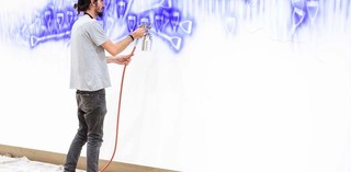 D Harding working on their commission Wall Composition in Reckitt’s Blue / Photograph: Chloe Callistemon © QAGOMA