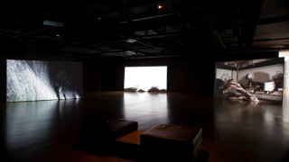 Hiraki Sawa, Japan b.1977 / Installation view O 2009 / Multi-channel video installation: 3-channel video projection exhibited from hard drive, HD video, 16:9, colour and black and white, 5-channel sound, 8:00 minutes; 10 channel video installation exhibited on customised LCD monitors, HD video transferred to DVD, 16:9, black and white, silent, 00:60 seconds; 5- channel sound by Organ Octet (edited by Dale Berning) exhibited on customised spinning speakers; customised metal light frames and light-bulb fixtures / Purchased 2010. Queensland Art Gallery Foundation / Collection: Queensland Art Gallery | Gallery of Modern Art / © Hiraki Sawa / Photographs: N Harth © QAGOMA