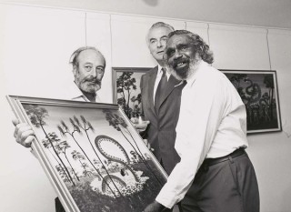 Percy Trezise and Dick Roughsey discuss a painting of the Rainbow Serpent with Prime Minister Gough Whitlam, 19 March 1975 / Collection: National Library of Australia / Photograph: Don Edwards/Australian Information Service