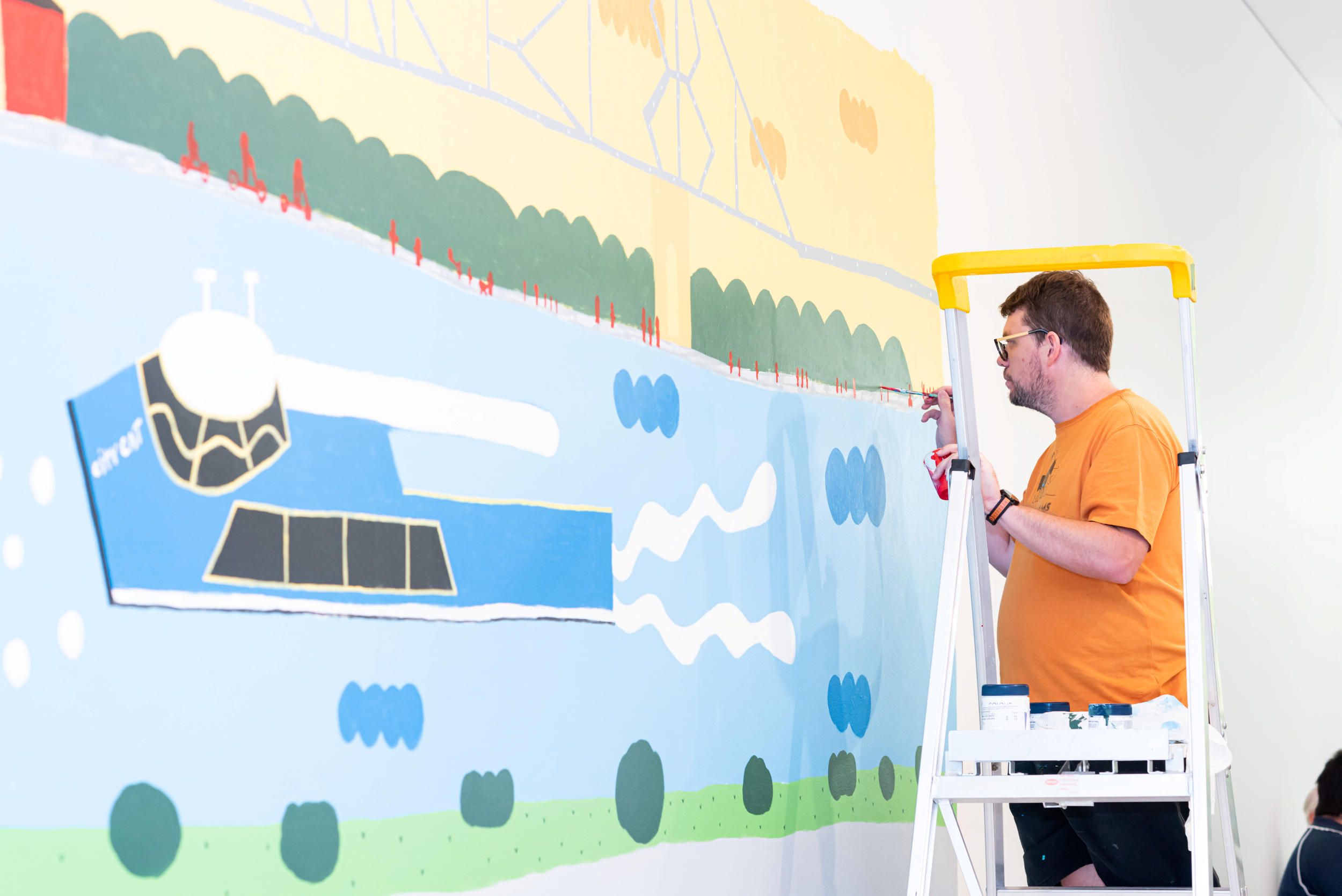 Artist & Autism Queensland ambassador Martin Edge installing his mural in the QAG Cafe, 2020 / Photograph: C Callistemon © QAGOMA