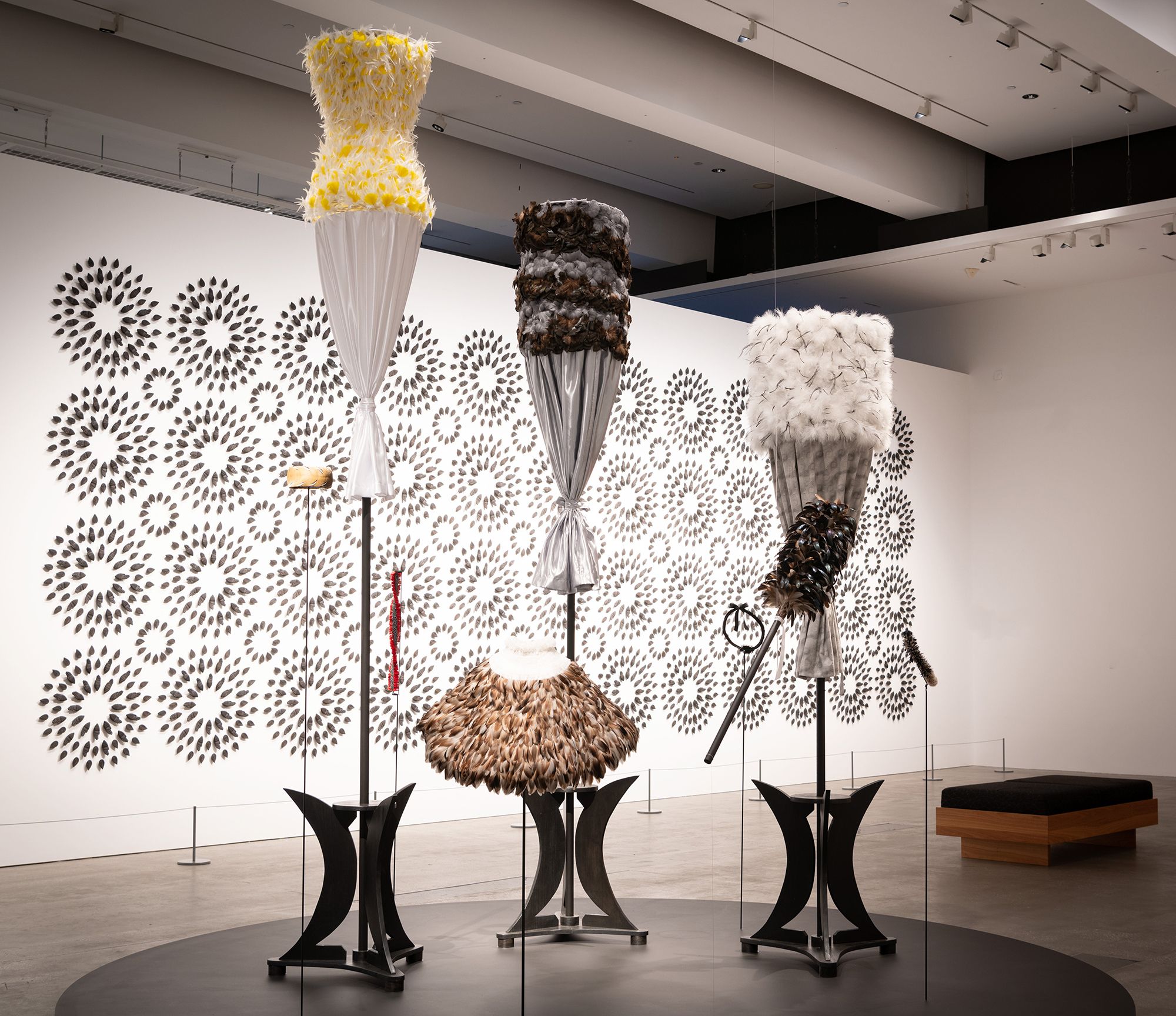 Mele Kahalepuna Chun, Kanaka ‘Ōiwi, Hawai‘i b.1966 / Hina 2024 / Feathers (goose, turkey, marabou, rooster, ringneck pheasant, guinea fowl and Lady Amherst’s pheasant), aluminium wire, floristry tape, tarred twine, satin and organza, wood, cotton thread and natural fibre cordage / Nine parts / 4 kāhili (feather standard) Māhealani (full moon); Pō Mākole (night rainbow); Hinaika‘opua (Hina in the clouds); Muku (dark night) / 4 lei (feather garland) Lua Kalai (red moon halo); Hinaikamālama (goddess of the moon); Mōhalu (crescent moon); Ke Ala O Ka Mahina (phases of the moon) / 1 ‘ahu‘ula (feather cloak) Mahinaokeao (Moon of the world) / Commissioned for ‘The 11th Asia Pacific Triennial of Contemporary Art’ / Purchased 2024 with funds from David Thomas AM through the QAGOMA Foundation / Collection: Queensland Art Gallery | Gallery of Modern Art / © Mele Kahalepuna Chun / (Background installation) Albert Yonathan Setyawan, Indonesia/Japan b.1983 / Spires of Undifferentiated Being 2023–24 / Terracotta / 3276 parts: 380 × 1140 × 3cm (installed) / Commissioned for ‘The 11th Asia Pacific Triennial of Contemporary Art’ / Purchased 2024 with funds from Tim Fairfax AC through the QAGOMA Foundation / Collection: Queensland Art Gallery | Gallery of Modern Art / © Albert Yonathan Setyawan / Photograph: J Ruckli © QAGOMA