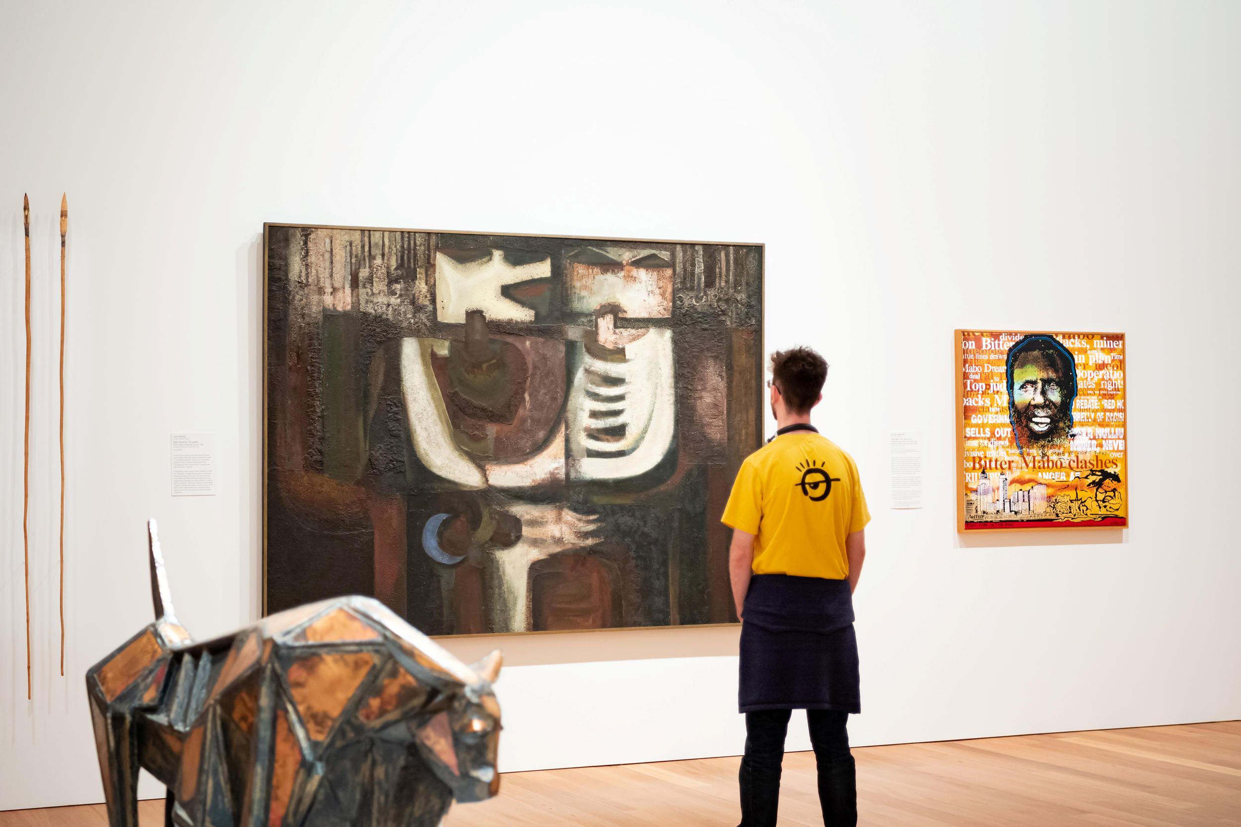 Left: Jon Molvig, 1923 - 1970 / Eden industrial: The garden (from 'Eden industrial' series) (installation view) 1961 / Oil treated with blow torch on composition board / 185 x 246.6cm / Purchased 1983 / Collection: Queensland Art Gallery | Gallery of Modern Art / © Otte Bartzis 

Right: John Citizen / Australia, 1955 - 2014 / Eddie Mabo (after Mike Kelley's 'Booth's Puddle' (installation view) 1985, from Plato's Cave, Rothko's Chapel, Lincoln's Profile) No2 1996 / Synthetic polymer paint on canvas / 100 x 100cm / The James C. Sourris AM Collection. Gift of James C. Sourris AM through the Queensland Art Gallery | Gallery of Modern Art Foundation 2019. Donated through the Australian Government's Cultural Gifts Program / Collection: Queensland Art Gallery | Gallery of Modern Art / © Estate of Gordon Bennett