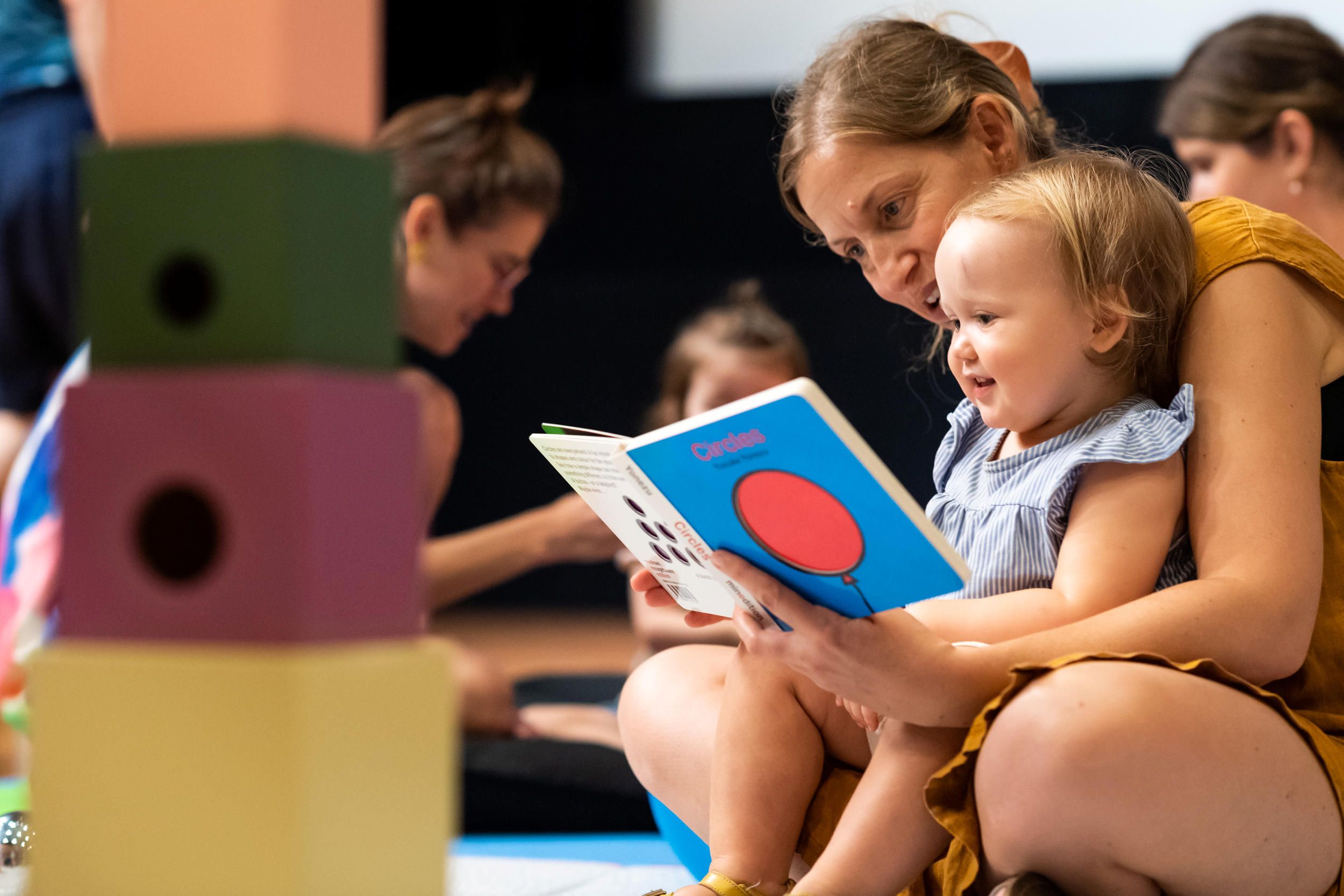 Art Play Date attendees reading a book, 2023 / Photo by M Campbell / ©QAGOMA
