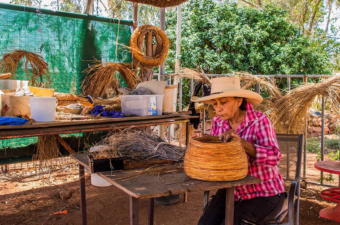 Shirley Macnamara working on spinifex vessels in her outdoor studio, Mount Guide Station, Mount Isa / Photograph: Virginia Hills