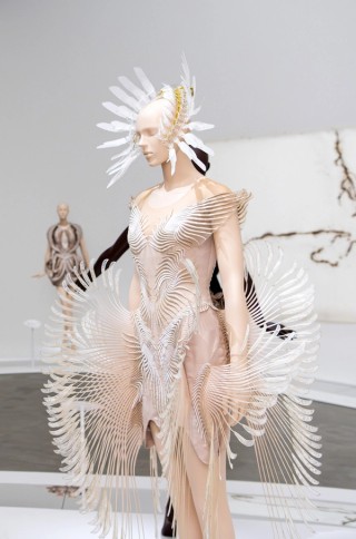 Iris van Herpen, Netherlands b.1984; Henosis dress, from the ‘Roots of Rebirth’ collection 2021; Cotton, laser-cut crepe, mylar, tulle, lace; Worn by model Natalia Vodianova at Iris van Herpen’s Haute couture Spring–Summer 2021 showing, as part of Paris Fashion Week; © & courtesy: Iris van Herpen atelier / Casey Curran for Iris van Herpen, United States b.1981; Henosis kinetic crown, from the ‘Roots of Rebirth’ collection 2021; Acrylic, brass, mylar, monofilament, geared motor; © & courtesy: Casey Curran