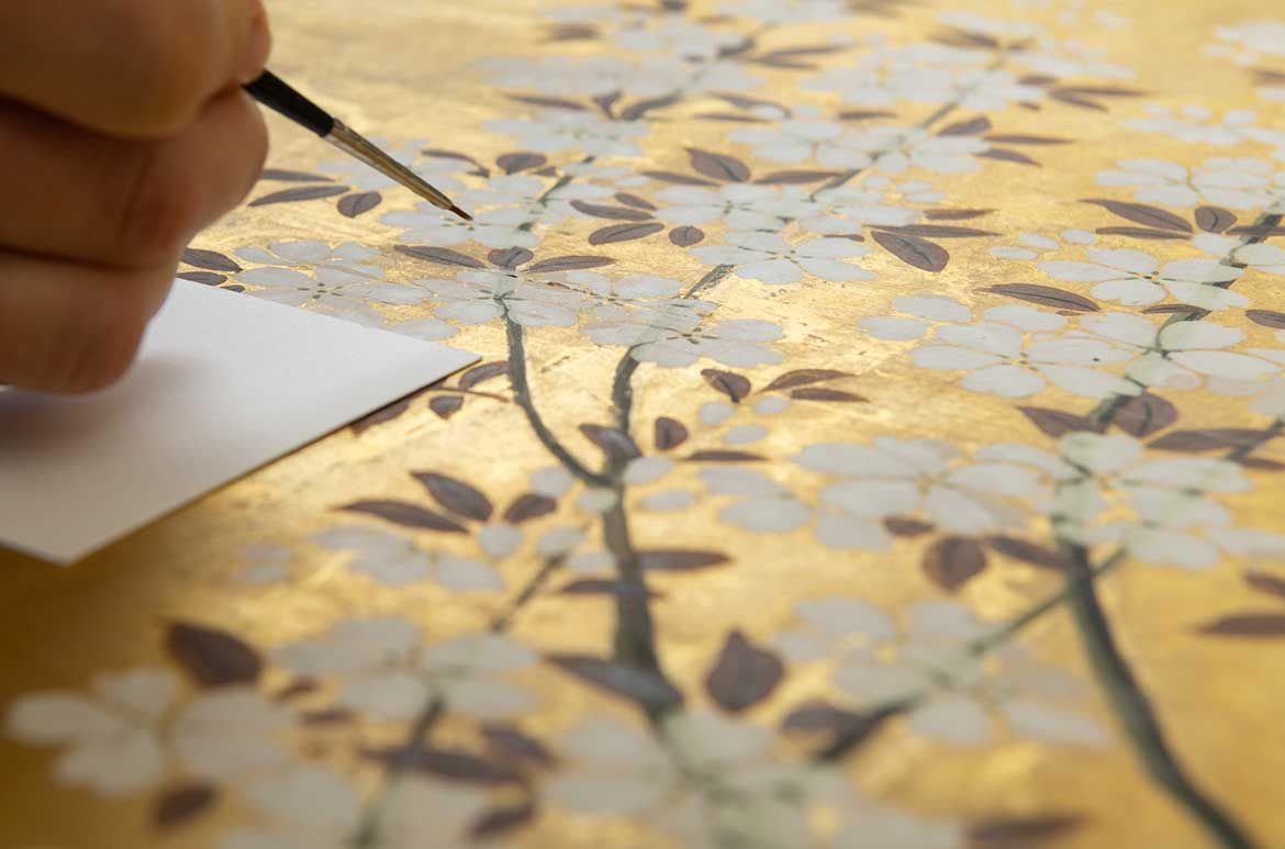 Kim Barrett consolidating the surface of the Six-fold screen with nobleman’s cart under a flowering cherry tree c.1650 / Photographs: N Harth and C Callistemon © QAGOMA
