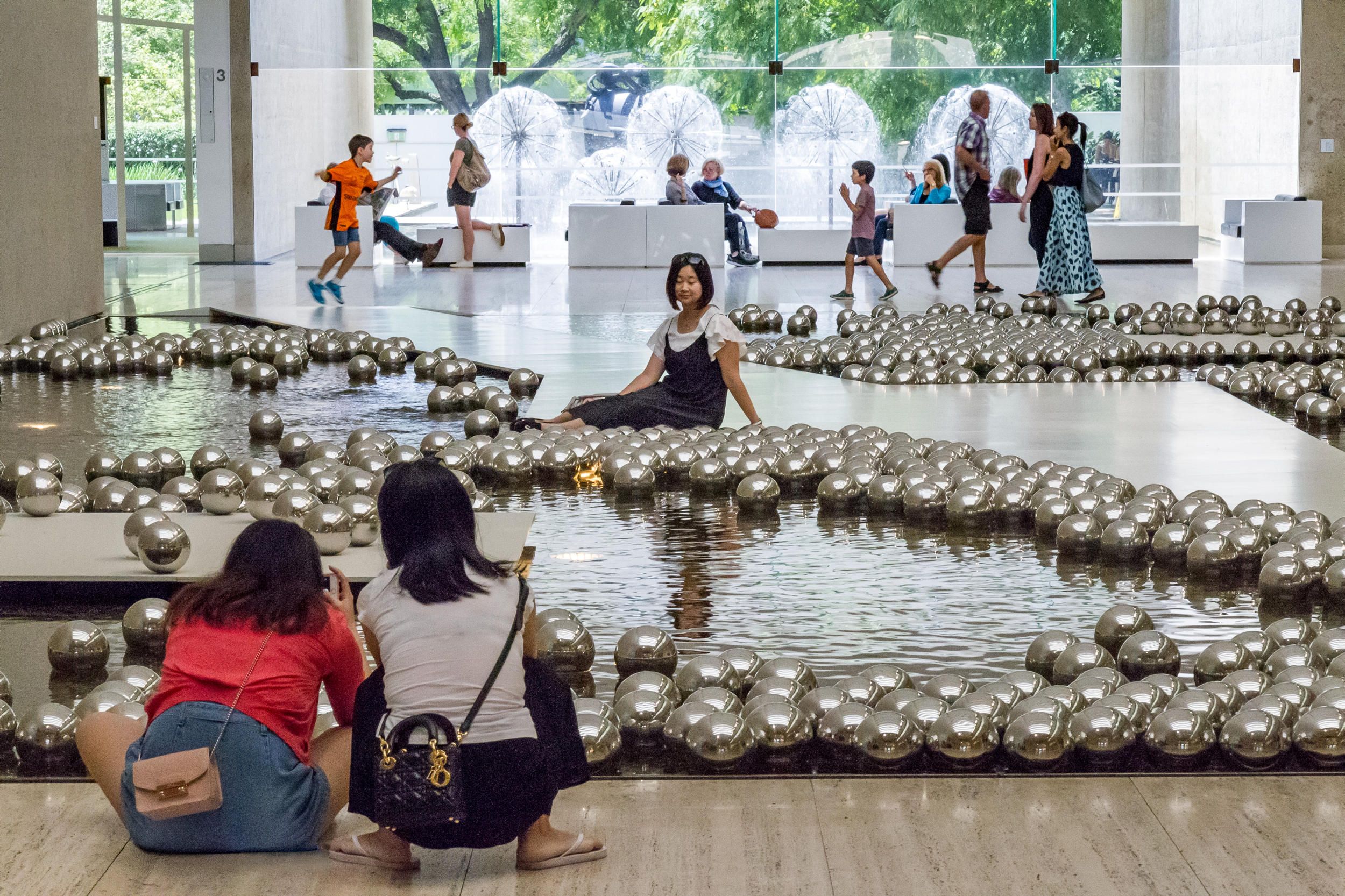 Visitors in the Queensland Art Gallery Watermall with Yayoi Kusama’s Narcissus garden 1966/2002 / Gift of the artist through the Queensland Art Gallery Foundation 2002 / Collection: Queensland Art Gallery | Gallery of Modern Art / © YAYOI KUSAMA / Photograph: B Wagner © QAGOMA