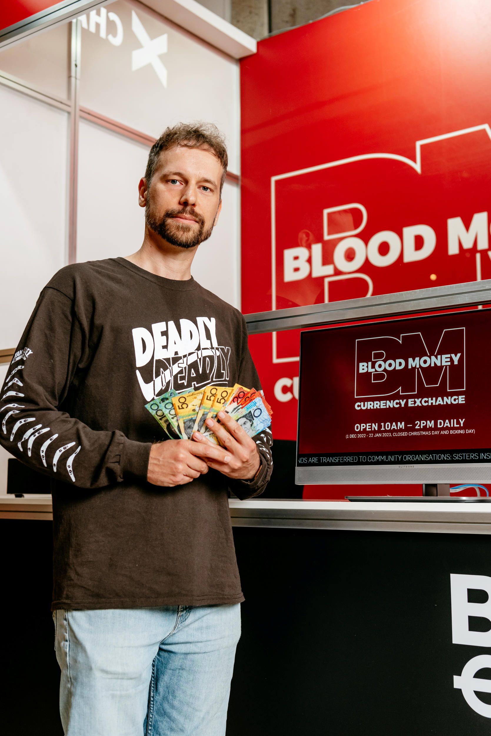 Artist Ryan Presley with Blood Money Currency Exchange Terminal 2018-ongoing (installation view) / Presented as part of ‘Embodied Knowledge: Queensland Contemporary Art’ / November 2022 / Image courtesy: Queensland Art Gallery | Gallery of Modern Art / Photograph: Joe Ruckli