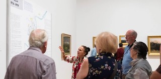 A Volunteer Guide engages visitors on a tour at the Queensland Art Gallery./ Photograph: K.Bennett. / © QAGOMA