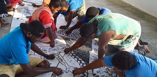 Jimmy K. Thaiday with community artists drawing on Sea Journey: people without borders 2018, Bethanie, Lifou, Photograph: Lynette Griffiths