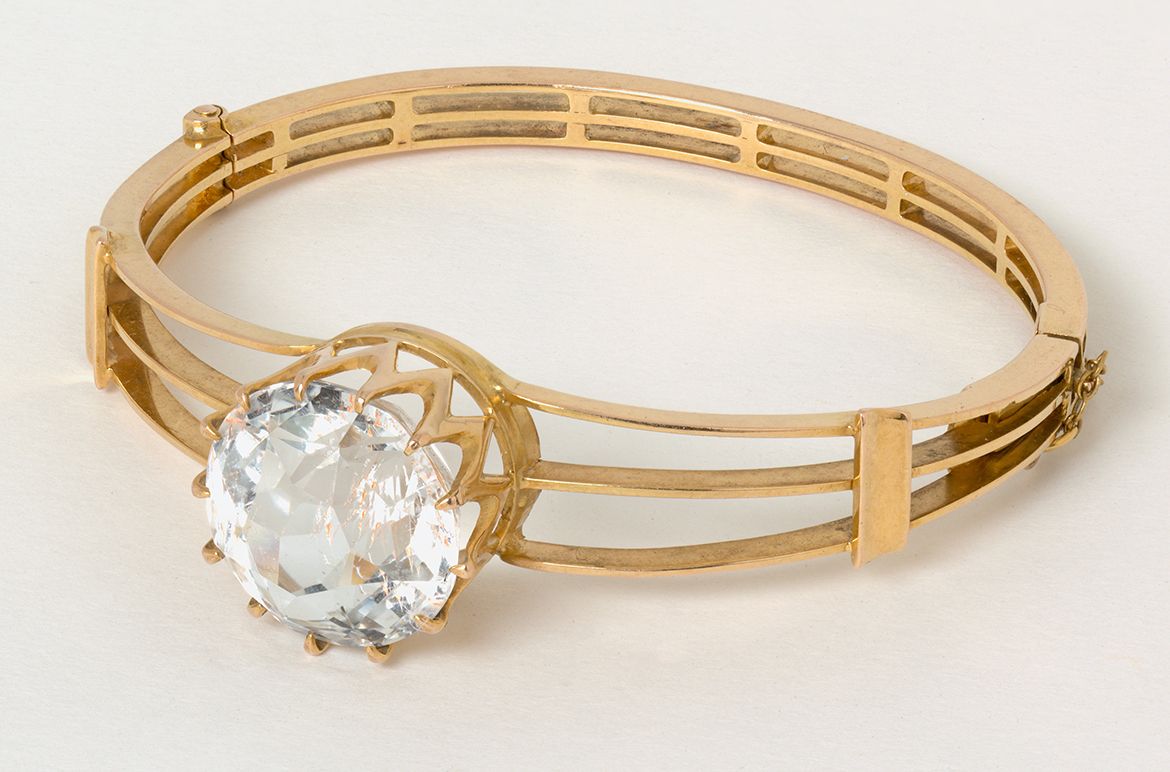 Mackay and Co. Australia active 1884–1982 / Gold and topaz bangle c.1900 / 18k yellow gold in hinged triple-bar design, set with a large central facetted topaz, approx. 22.5cts / 5.5cm (inside diam.); 24 grams (weight) / Purchased 2020. Queensland Art Gallery | Gallery of Modern Art Foundation / Collection: Queensland Art Gallery | Gallery of Modern Art