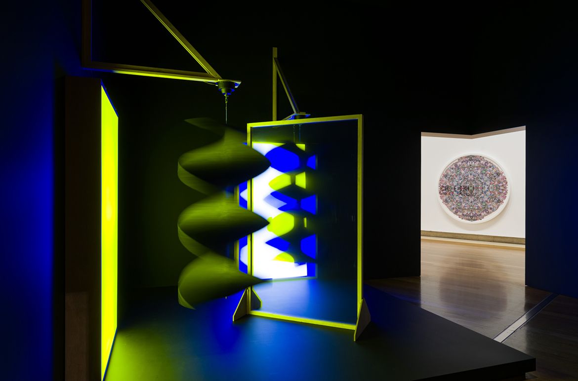 Taree Mackenzie’s Pepper’s ghost, wind turners, blue and yellow 2018 installed for ‘Living Patterns’, with Jemima Wyman’s Aggregate Icon (Kaleidoscopic Catchment) 2014 visible in the background, Queensland Art Gallery 2023 / Collection: Queensland Art Gallery | Gallery of Modern Art / © The artists / Photograph: C Callistemon © QAGOMA