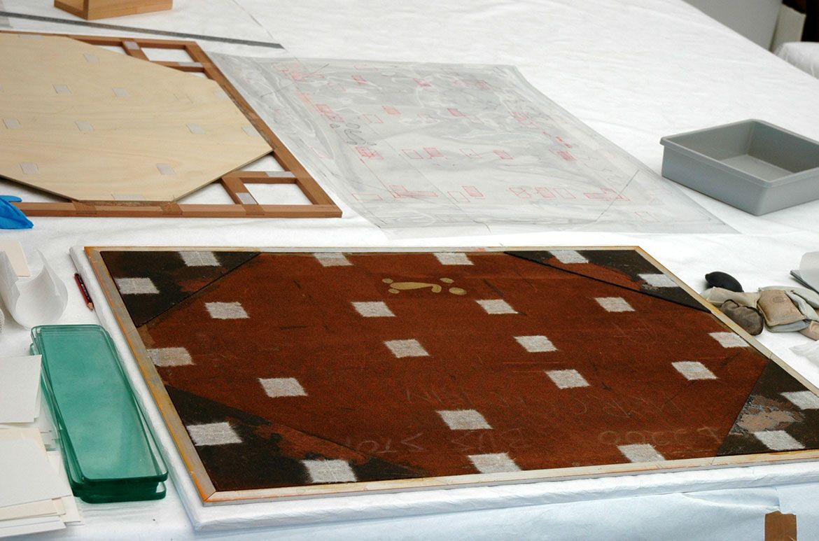 The verso of Bus stop 1965 being prepared for mounting. Removable Japanese tissue tabs are adhered in locations where Velcro will later be attached. The cradle is in the background and in this case required a plywood insert that fits within previously attached Masonite corners on the verso of the artwork