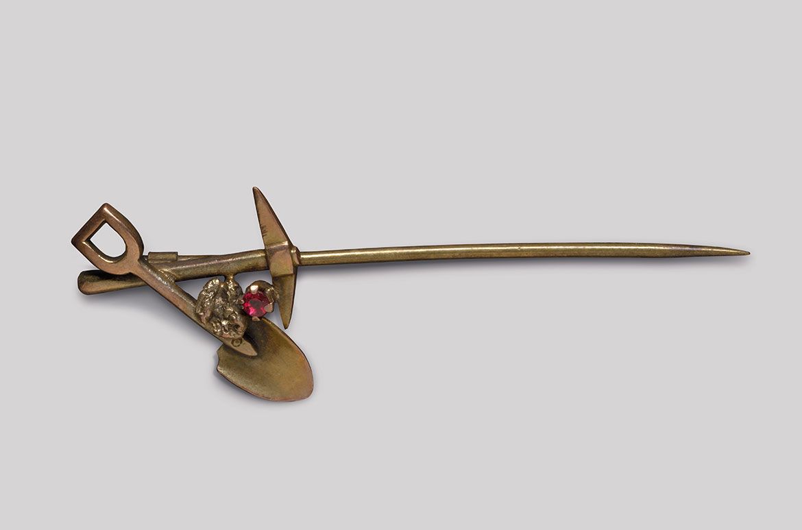 Goldfields stick-pin (crossed pick and shovel with garnet) c.1880–1915 / Gold, gold nugget and garnet / 5.2 x 2 x 0.5cm
Acc. 2011.105