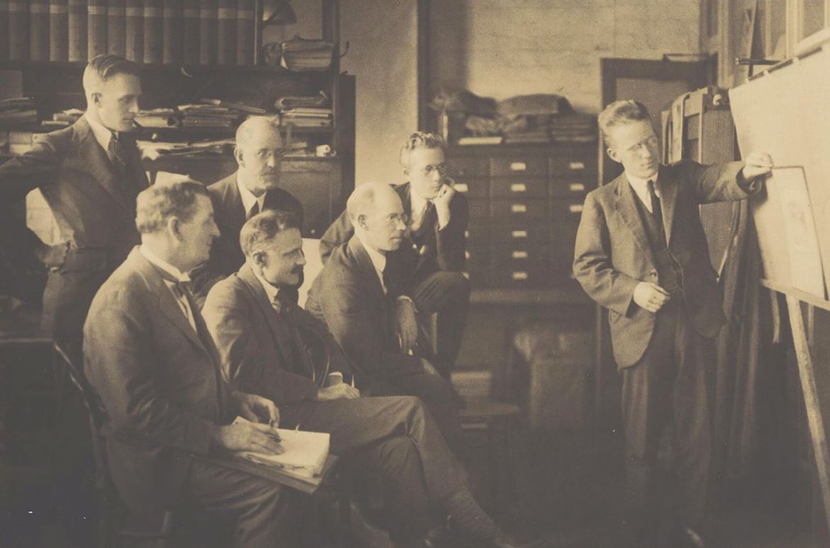Harold Cazneaux, 1878-1953, photographer / Members of the Sydney Camera Circle, Sydney c.1924 / Left to right at back: H. Bedggood, W.S. White and Cecil W. Bostock; Left to right on front: J.G. McCall, Henri Mallard and Stanley W Eutrope; W. Lamond standing and assisting with photographs on front / Sepia toned photograph / 10.2 x 16.2cm / 6808692 / Courtesy: National Library of Australia