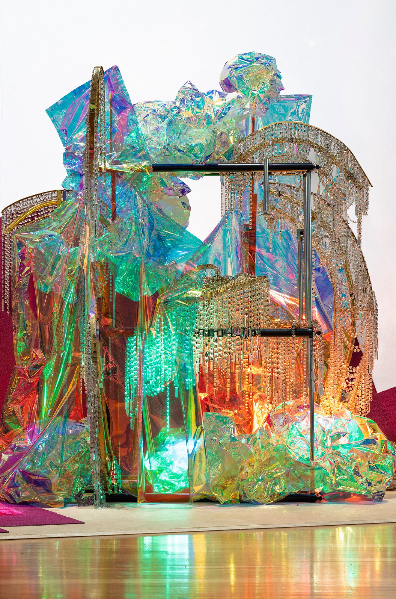Justene Williams, Queensland Australia b.1970 / Crystal whisperer 2026 (installation view, ‘Justene Williams: Once We Were Mudskippers’, Queensland Art Gallery, Brisbane, 2026) / Found chandelier, found clothes rack, vinyl, lights / Supported by the Queensland Government through Arts Queensland and the Australian Government through Creative Australia, its principal arts investment and advisory body / Courtesy: Justene Williams / Photograph: N Umek © QAGOMA