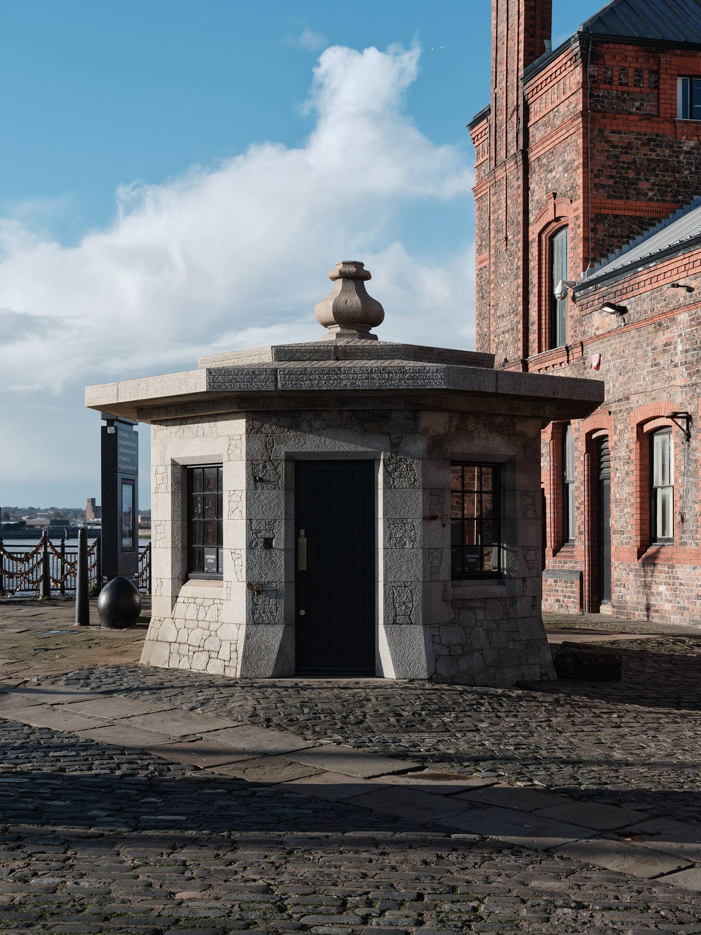A photograph of a stone hut with open door on a waterfront